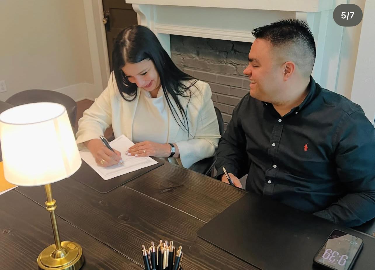 Clients signing closing documents with Alvear Group